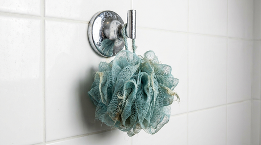 Fleur de douche en plastique usée accrochée dans une douche carrelée